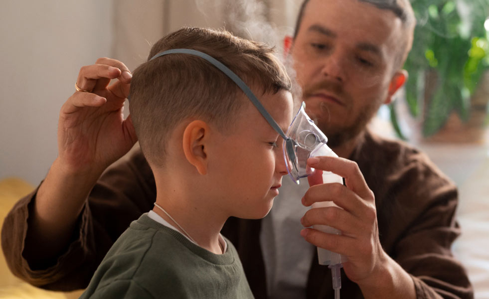 Padre administrando tratamiento con un nebulizador a su hijo pequeño.