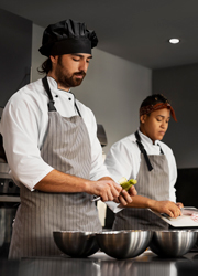 Un cocinero y una cocinera en una cocina trabajando