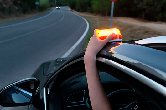 una persona pone un luz de emergencia v16 en el techo de su vehículo