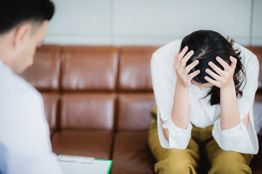 Mujer con depresión cogiéndose la cabeza en un consultorio