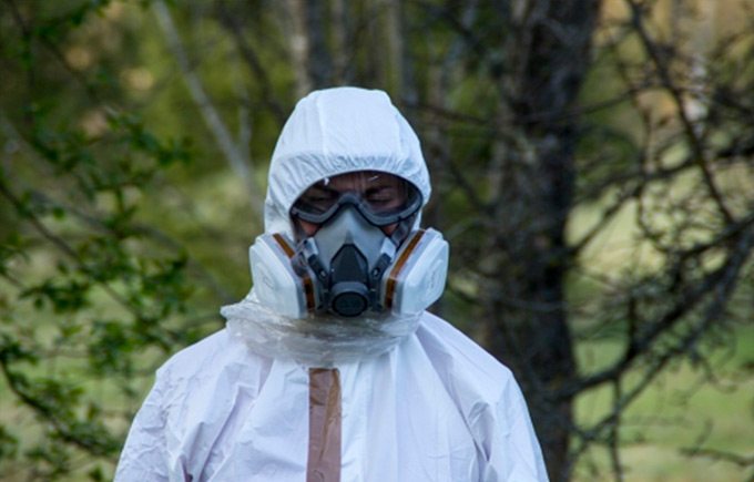persona equipada con un traje de protección NBQ completo y máscara respiratoria de doble filtro en un entorno natura