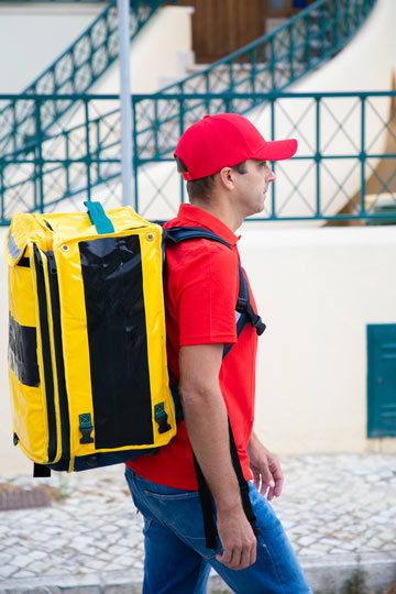 Persona con su mochila de reparto isotérmica amarilla listo para entregar un pedido a domicilio